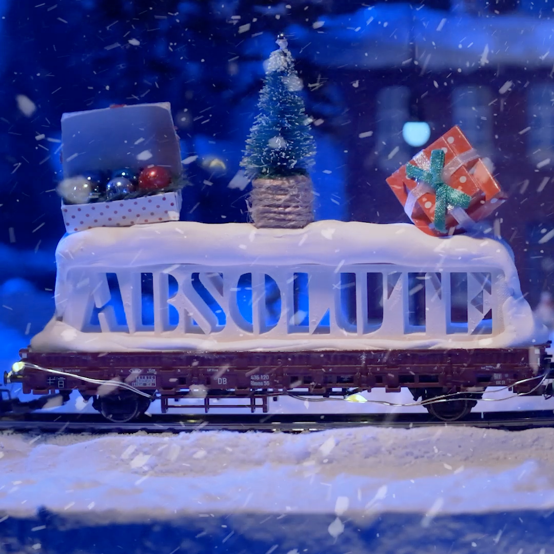 En 3D-printad last där det står "Absolut" i stor text som urtag i ett block, på en lastvagn på modelljärnväg.